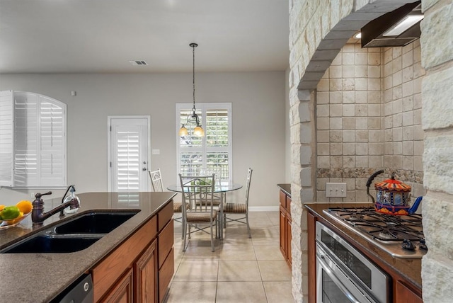 kitchen featuring pendant lighting, dark stone counters, sink, light tile patterned floors, and appliances with stainless steel finishes