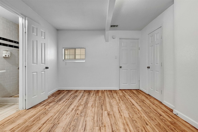 unfurnished bedroom with connected bathroom and light wood-type flooring