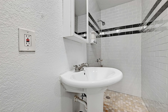 bathroom featuring sink and a tile shower