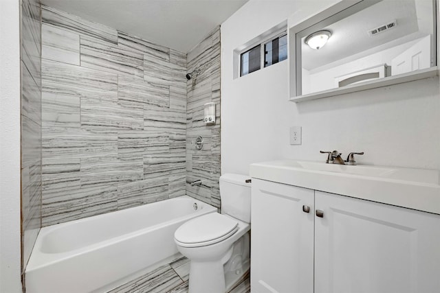 full bathroom featuring vanity, tiled shower / bath, and toilet