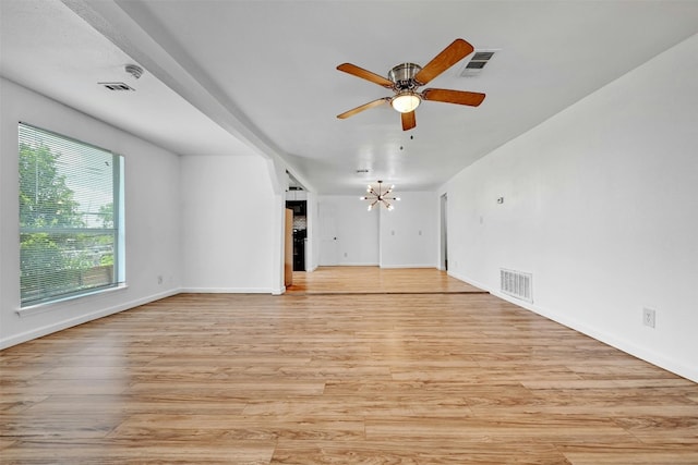 unfurnished living room with ceiling fan with notable chandelier and light wood-type flooring