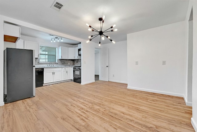 kitchen featuring tasteful backsplash, white cabinets, black appliances, an inviting chandelier, and light hardwood / wood-style flooring