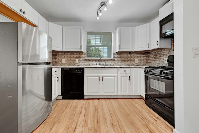 kitchen featuring white cabinetry, light stone countertops, and black appliances