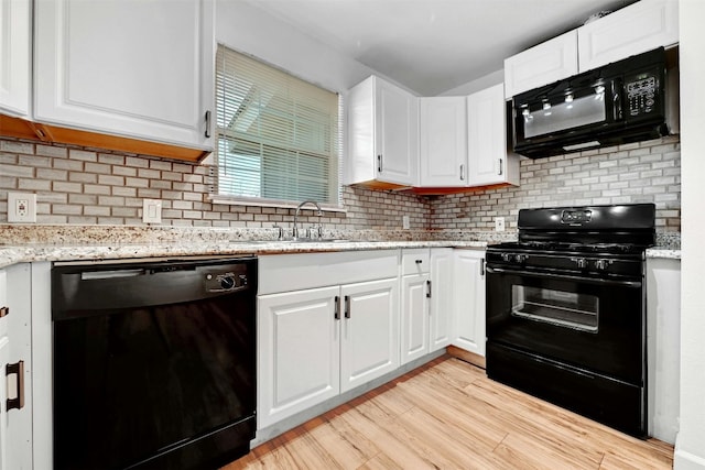 kitchen featuring white cabinetry, backsplash, black appliances, and sink