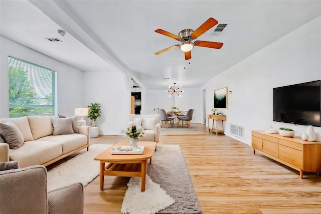 living room featuring ceiling fan with notable chandelier and light wood-type flooring