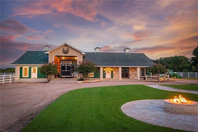 back house at dusk featuring a yard and a fire pit