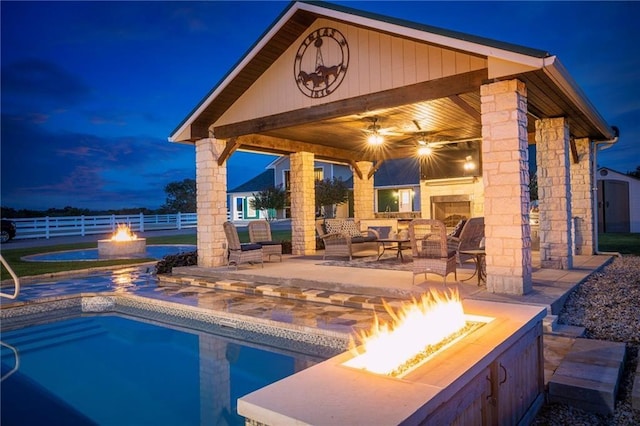 view of pool featuring a patio area, ceiling fan, and an outdoor living space with a fire pit