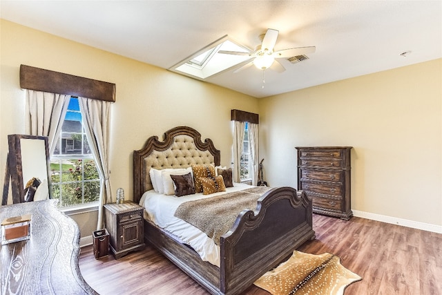 bedroom featuring ceiling fan, wood-type flooring, and a skylight