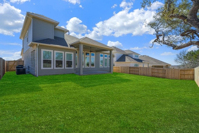 rear view of house with ceiling fan and a lawn