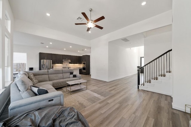 living room featuring sink, light wood-type flooring, and ceiling fan