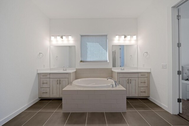 bathroom featuring tile patterned flooring, tiled bath, and vanity