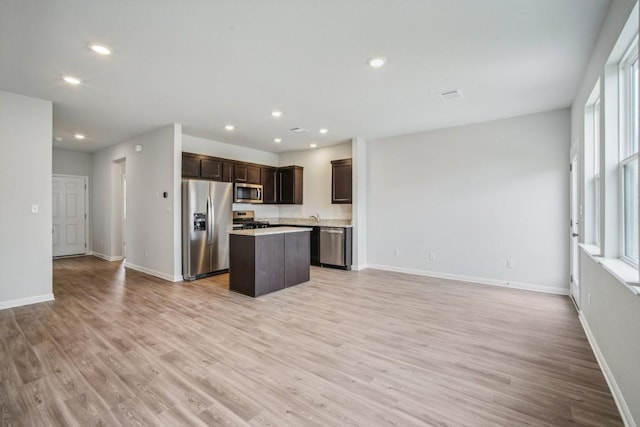 kitchen featuring stainless steel appliances, a center island, dark brown cabinetry, and light hardwood / wood-style flooring