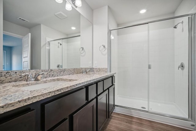 bathroom featuring wood-type flooring, a shower with door, and vanity