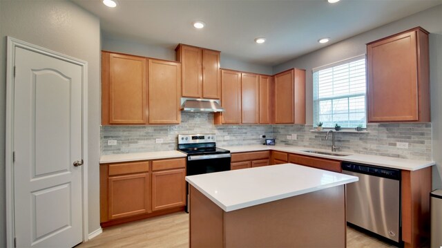 kitchen featuring a kitchen island, light hardwood / wood-style flooring, appliances with stainless steel finishes, backsplash, and sink