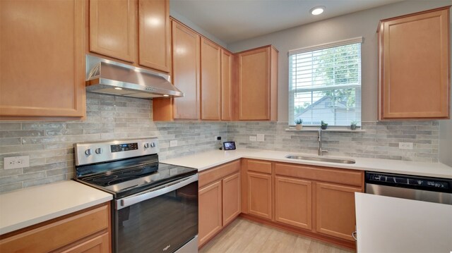 kitchen featuring stainless steel appliances, sink, light hardwood / wood-style floors, and tasteful backsplash