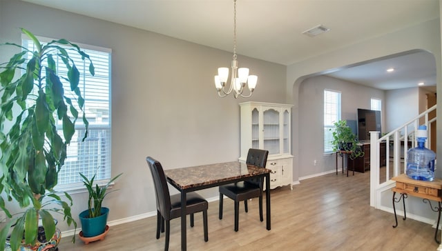 dining space with light hardwood / wood-style floors and a notable chandelier