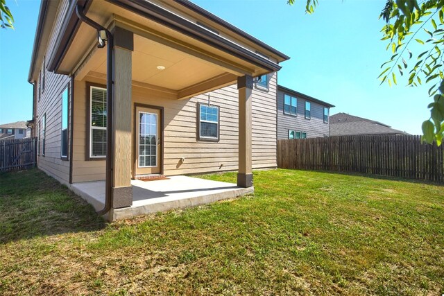 rear view of property featuring a lawn and a patio area