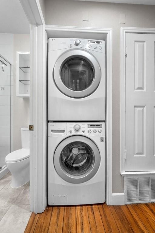 washroom featuring stacked washer and dryer and light hardwood / wood-style flooring