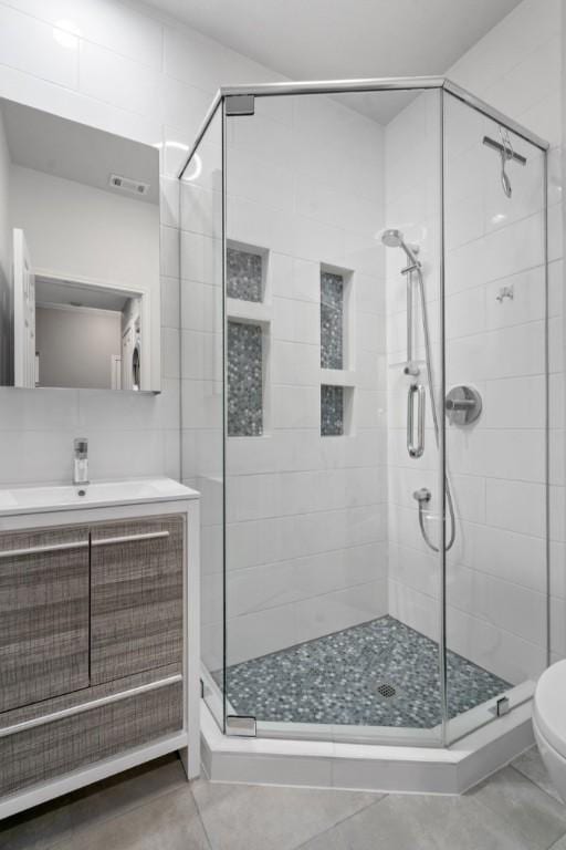 bathroom featuring tile patterned floors, vanity, toilet, and a shower with door