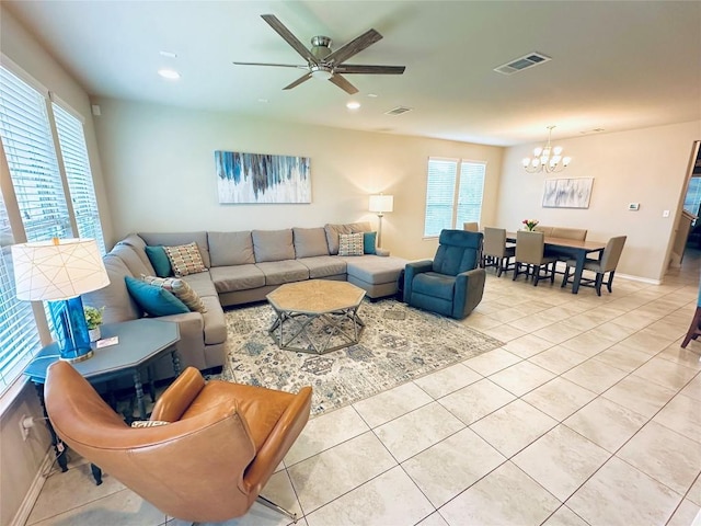 living room with light tile patterned flooring, a healthy amount of sunlight, and ceiling fan with notable chandelier