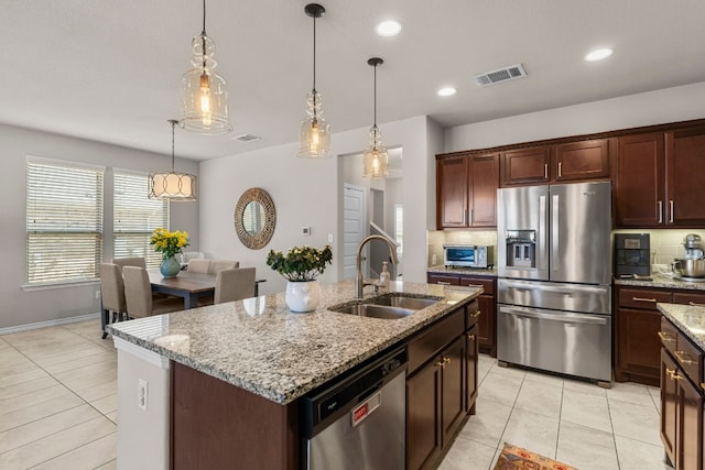 kitchen featuring stainless steel appliances, pendant lighting, light tile patterned floors, sink, and a kitchen island with sink