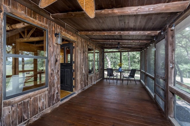 unfurnished sunroom with lofted ceiling with beams, a wealth of natural light, and wooden ceiling