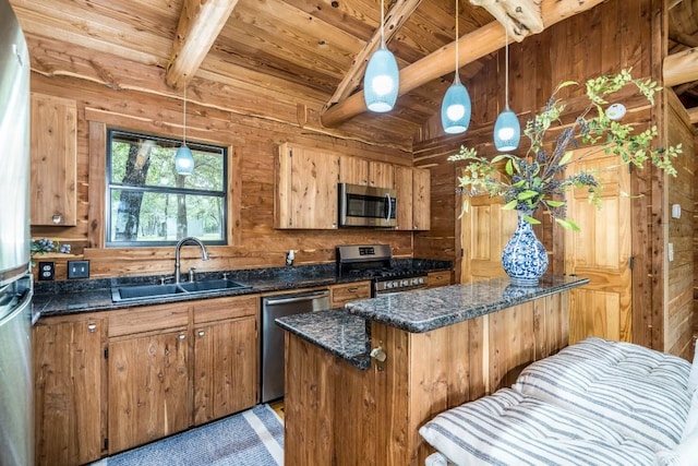 kitchen with appliances with stainless steel finishes, wooden walls, sink, decorative light fixtures, and beamed ceiling