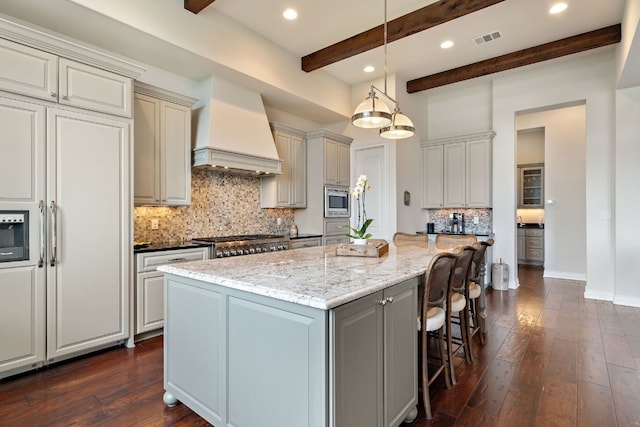 kitchen with pendant lighting, range, light stone counters, custom range hood, and a kitchen island