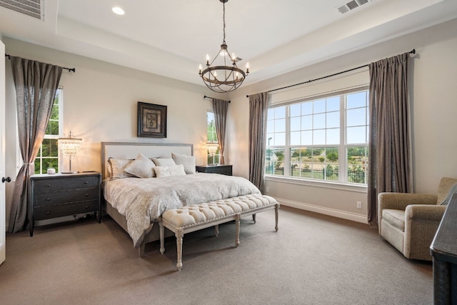 carpeted bedroom with an inviting chandelier and a raised ceiling