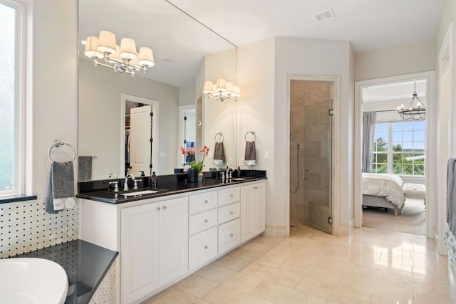 bathroom featuring an inviting chandelier, tile patterned floors, vanity, and a shower with shower door