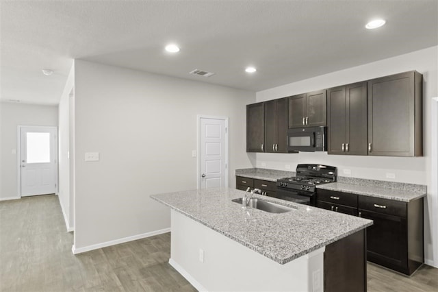 kitchen featuring a kitchen island with sink, sink, black appliances, and light hardwood / wood-style floors