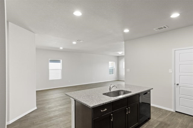 kitchen with dishwasher, sink, an island with sink, and light hardwood / wood-style flooring