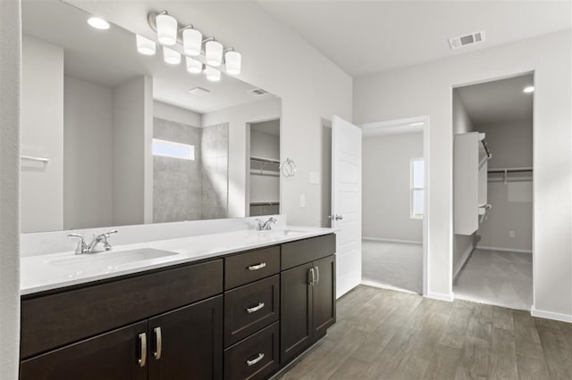 bathroom featuring hardwood / wood-style floors, vanity, and a tile shower