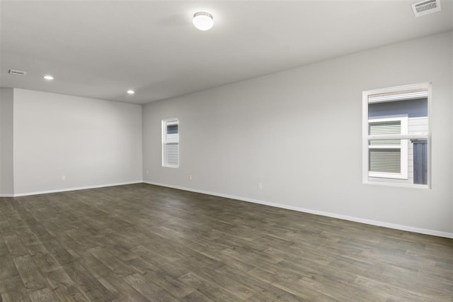 unfurnished room with visible vents, baseboards, and dark wood-style flooring