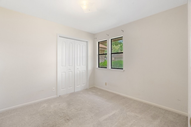 unfurnished bedroom with light colored carpet and a closet