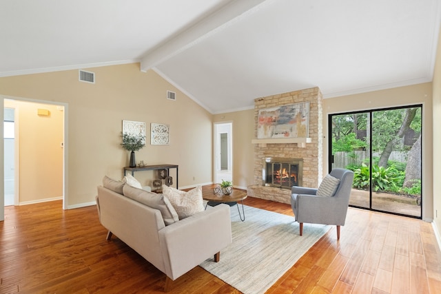 living room featuring hardwood / wood-style flooring, lofted ceiling with beams, a stone fireplace, and ornamental molding