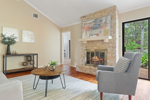 living room featuring high vaulted ceiling, wood-type flooring, crown molding, and a stone fireplace