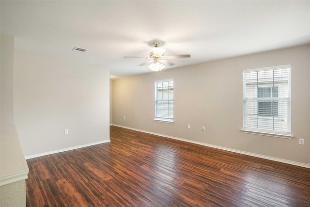 empty room with ceiling fan, dark wood-type flooring, and a wealth of natural light