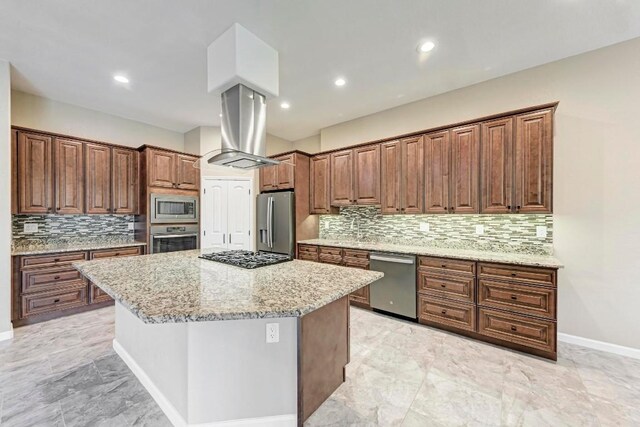 kitchen with island exhaust hood, light stone countertops, a center island, and appliances with stainless steel finishes