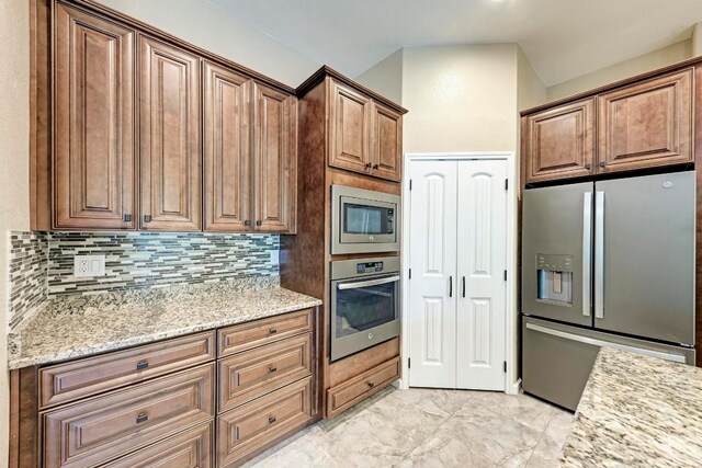 kitchen with decorative backsplash, appliances with stainless steel finishes, and light stone counters