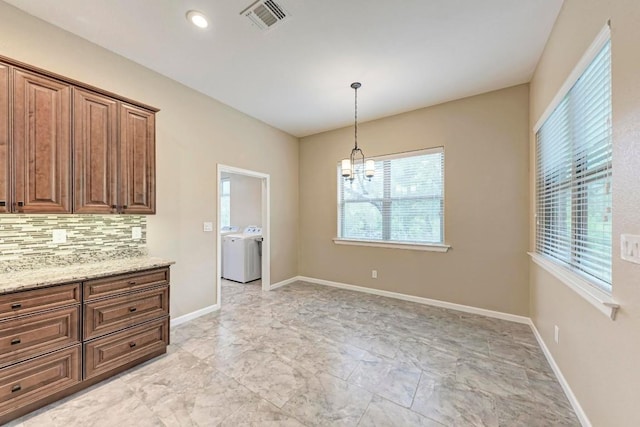 unfurnished dining area featuring separate washer and dryer, a wealth of natural light, and a chandelier