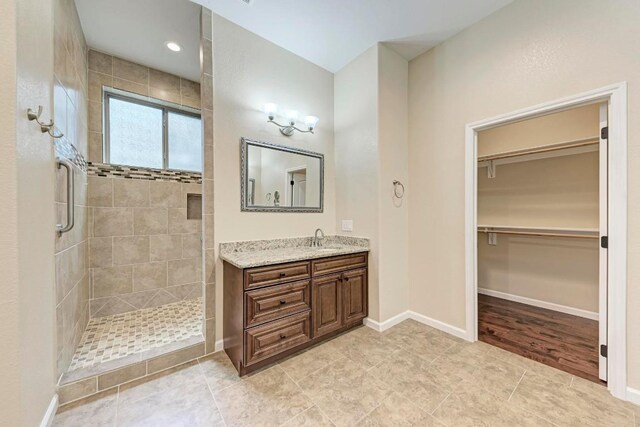 bathroom with tiled shower, vanity, and tile patterned flooring