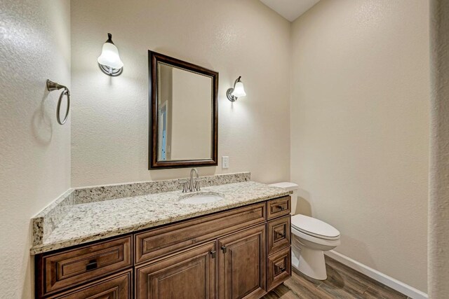 101 Lost Buck, Horseshoe Bay, TX 78657 - bathroom with wood finished floors, toilet, vanity, and baseboards