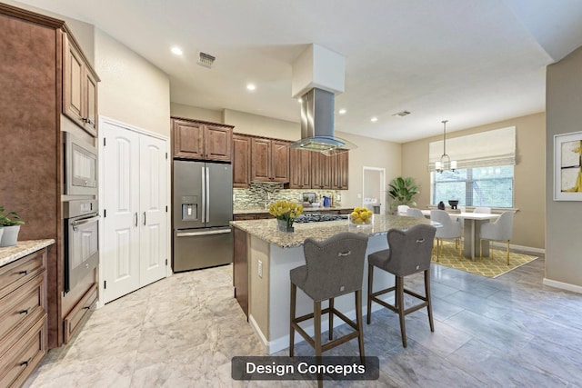 kitchen featuring decorative backsplash, appliances with stainless steel finishes, light stone counters, island range hood, and a kitchen island