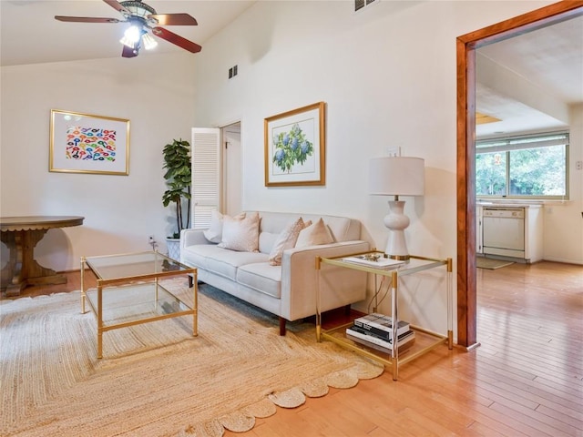 living room with hardwood / wood-style flooring, ceiling fan, and high vaulted ceiling