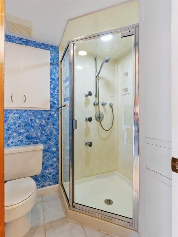 bathroom featuring tile patterned floors, a shower with shower door, and toilet