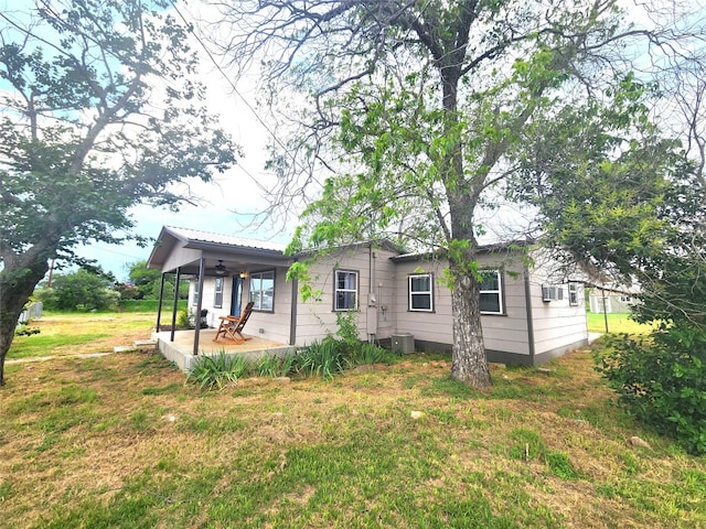 back of property with central AC unit and a yard