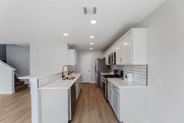 kitchen featuring a breakfast bar, white cabinets, sink, light wood-type flooring, and appliances with stainless steel finishes