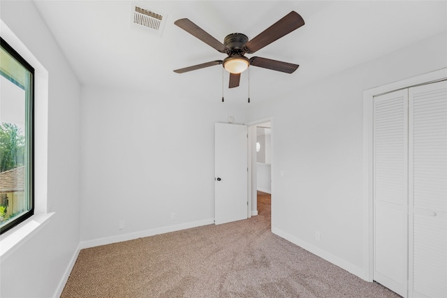 unfurnished bedroom with ceiling fan, light colored carpet, multiple windows, and a closet