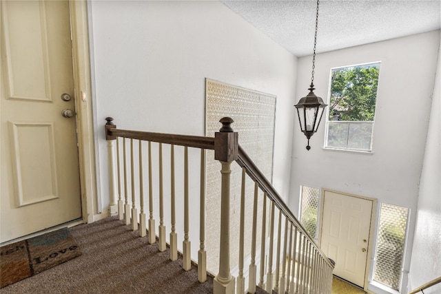 stairs with carpet and a textured ceiling